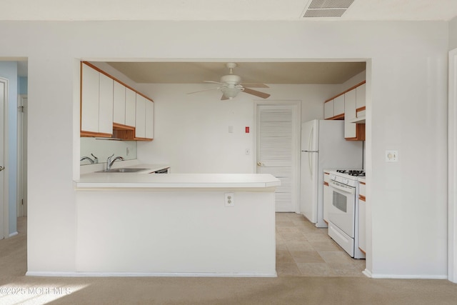 kitchen with white cabinetry, white gas range, kitchen peninsula, and sink