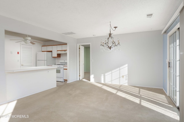 kitchen with light carpet, white appliances, decorative light fixtures, and a textured ceiling