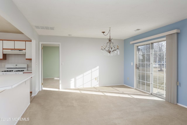 unfurnished dining area with an inviting chandelier and light colored carpet