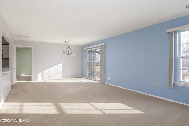 carpeted spare room with a notable chandelier