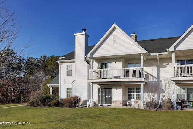 rear view of property with a balcony and a yard