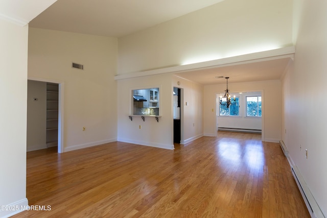 unfurnished living room featuring a notable chandelier, a baseboard radiator, and hardwood / wood-style floors