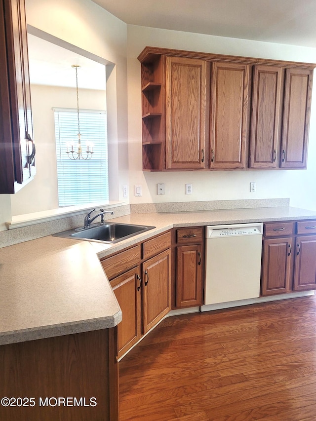 kitchen with pendant lighting, sink, dark wood-type flooring, white dishwasher, and a notable chandelier