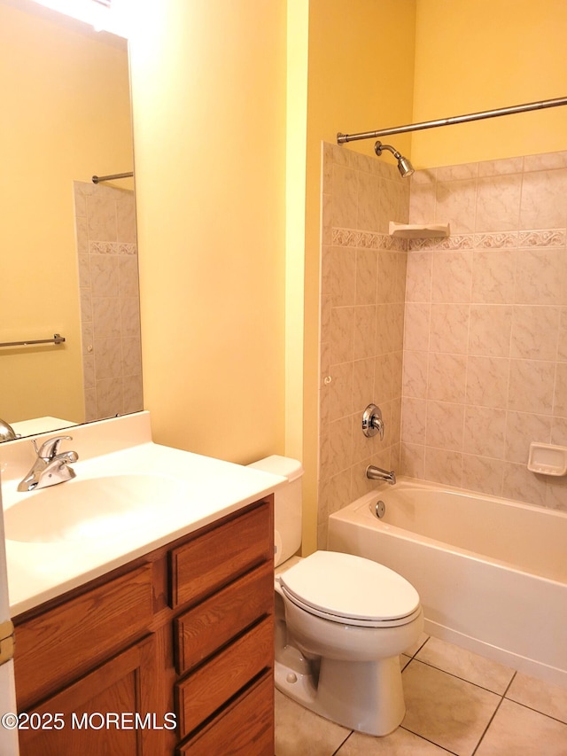 full bathroom with tile patterned flooring, tiled shower / bath, vanity, and toilet