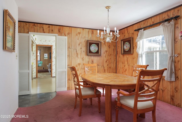 dining space with wooden walls, a chandelier, and dark carpet