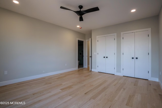 unfurnished bedroom featuring ceiling fan, two closets, and light hardwood / wood-style floors