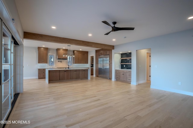 kitchen with decorative light fixtures, a center island, light wood-type flooring, stainless steel built in fridge, and ceiling fan