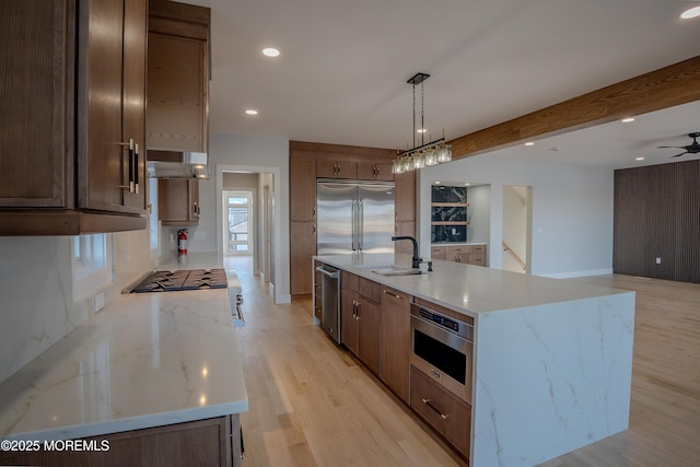 kitchen featuring appliances with stainless steel finishes, sink, an island with sink, and hanging light fixtures