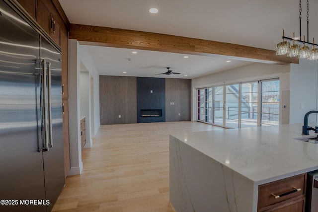 kitchen featuring beamed ceiling, ceiling fan, built in fridge, and hanging light fixtures