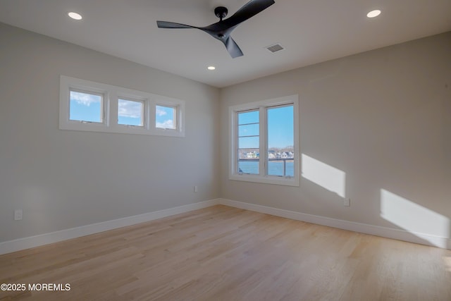 empty room featuring light hardwood / wood-style flooring, ceiling fan, and a water view