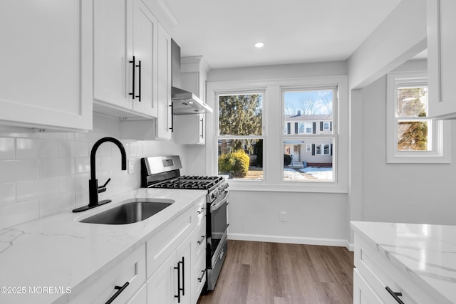 kitchen featuring light stone counters, gas range, and white cabinetry