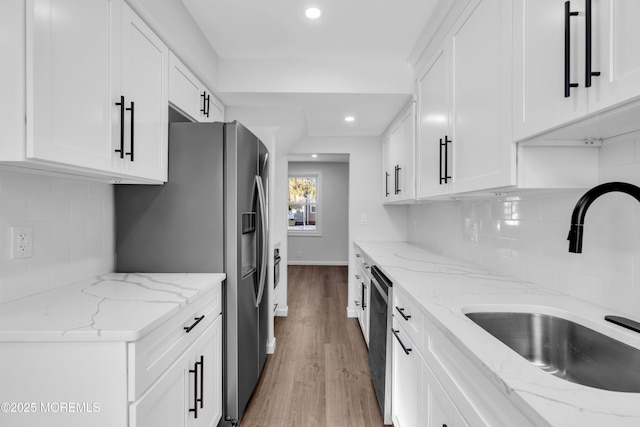 kitchen featuring white cabinetry, sink, light stone countertops, and appliances with stainless steel finishes