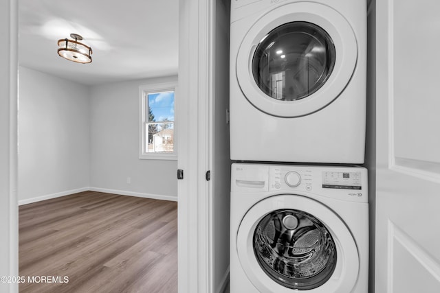 laundry room with stacked washing maching and dryer and light hardwood / wood-style floors