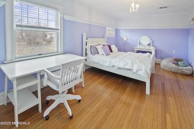 bedroom with hardwood / wood-style floors, multiple windows, and a notable chandelier