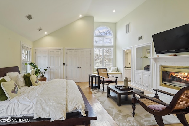 bedroom featuring a towering ceiling, light hardwood / wood-style floors, and two closets