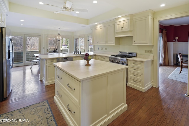 kitchen featuring sink, decorative light fixtures, appliances with stainless steel finishes, kitchen peninsula, and a kitchen island