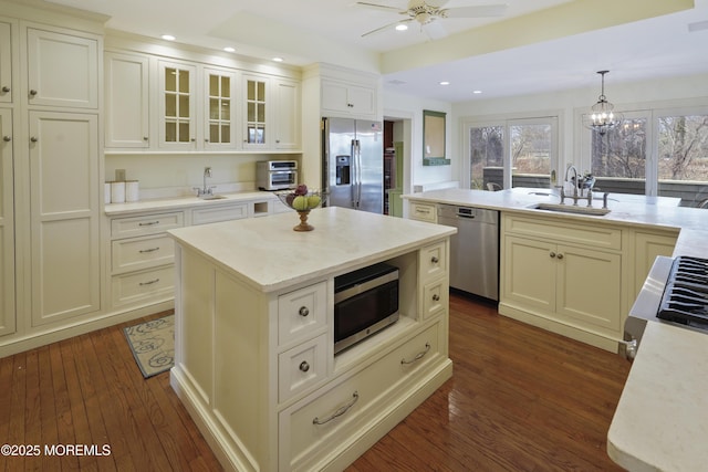 kitchen featuring pendant lighting, sink, dark wood-type flooring, appliances with stainless steel finishes, and a kitchen island