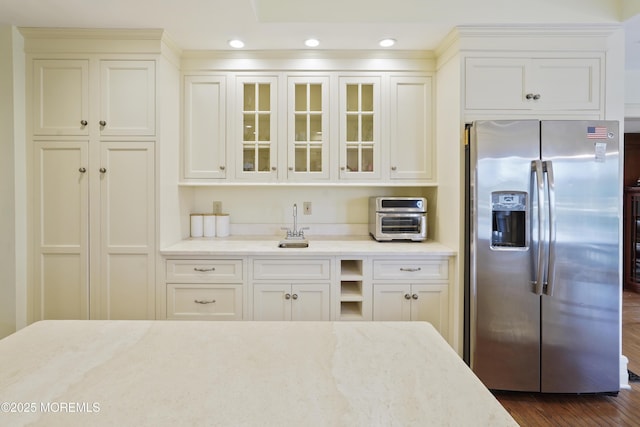 kitchen featuring stainless steel refrigerator with ice dispenser, dark hardwood / wood-style floors, sink, and light stone counters