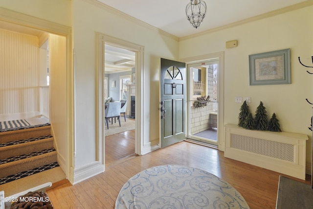 entryway with ornamental molding and light hardwood / wood-style floors