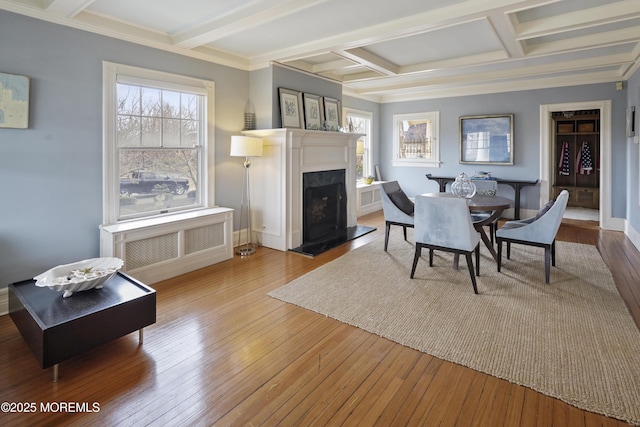 dining area featuring coffered ceiling, a fireplace, beam ceiling, and light wood-type flooring