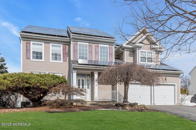 view of front of house with aphalt driveway, a porch, a garage, solar panels, and a front lawn