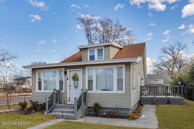 bungalow-style home featuring a wooden deck and a front lawn