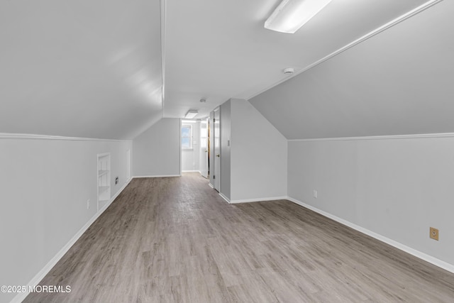 additional living space with vaulted ceiling and light hardwood / wood-style flooring