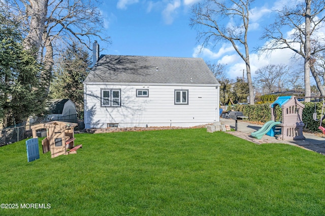 back of house featuring a playground and a lawn