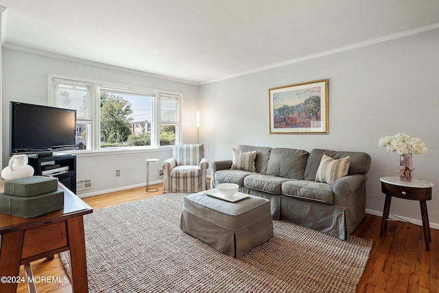 living area with visible vents, crown molding, baseboards, and wood finished floors