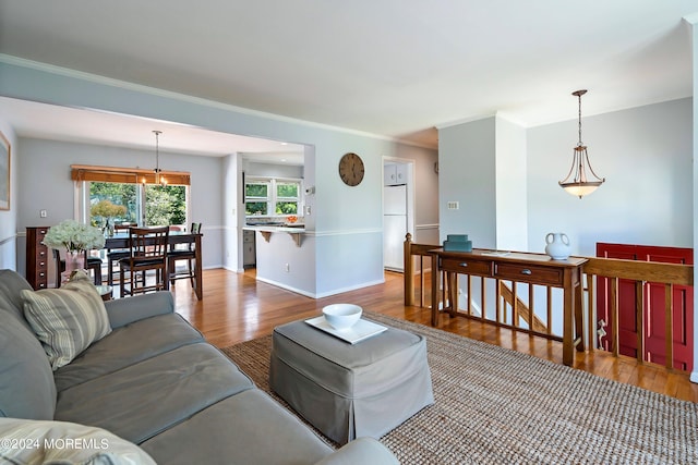 living room featuring light wood-type flooring, baseboards, and ornamental molding