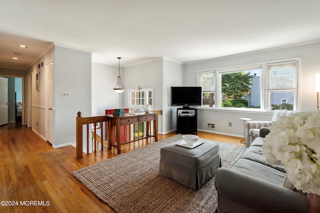 living area with baseboards, crown molding, and hardwood / wood-style floors