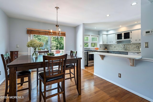 dining area with a chandelier, wood finished floors, and recessed lighting