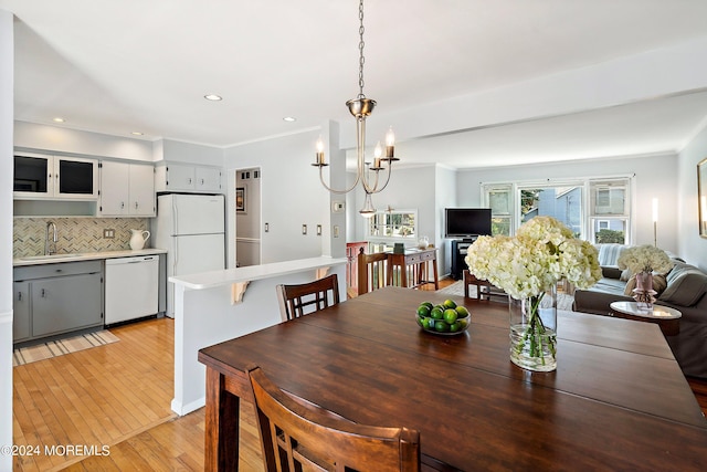 dining space featuring light wood-style floors, recessed lighting, ornamental molding, and an inviting chandelier