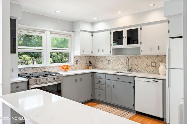 kitchen with white appliances, light wood-style floors, a sink, and gray cabinetry