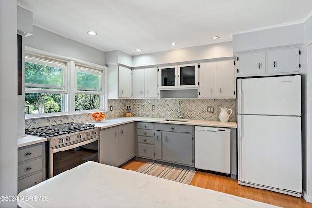 kitchen featuring white appliances, gray cabinets, a sink, and light countertops