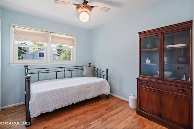 bedroom featuring light wood finished floors, a ceiling fan, and baseboards