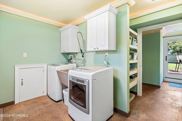 clothes washing area with a sink, washing machine and clothes dryer, cabinet space, and baseboards