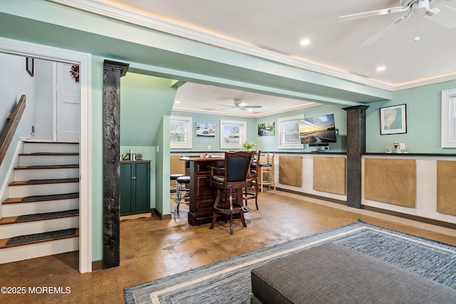 dining room with crown molding, finished concrete floors, ceiling fan, bar area, and stairs