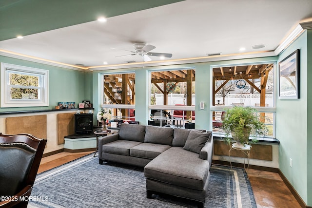 living room with recessed lighting, visible vents, baseboards, a wood stove, and crown molding