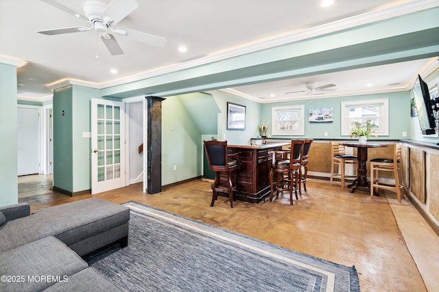 dining room featuring baseboards, a ceiling fan, wet bar, crown molding, and recessed lighting