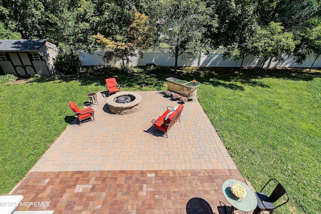 view of patio with a shed, an outdoor fire pit, an outdoor structure, and a fenced backyard