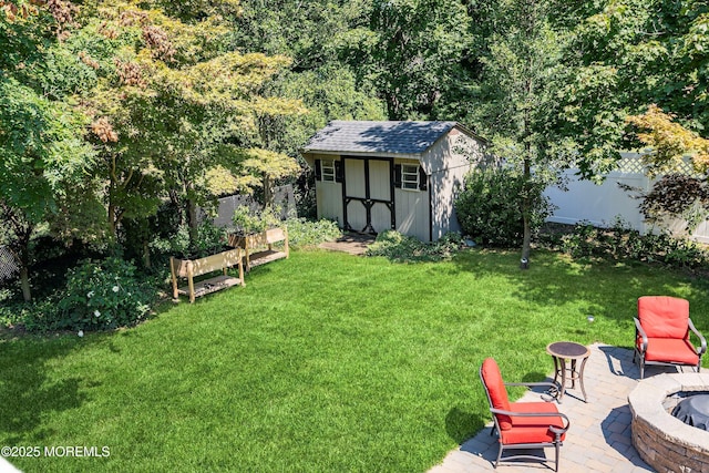 view of yard with a fenced backyard, a fire pit, an outdoor structure, a storage unit, and a patio area