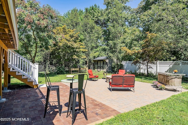 view of patio / terrace featuring a storage unit, stairs, fence, and an outdoor structure