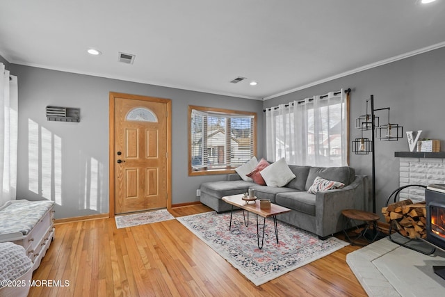 living room featuring crown molding, a brick fireplace, and light hardwood / wood-style floors