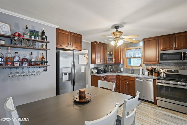 kitchen featuring sink, tasteful backsplash, crown molding, ceiling fan, and stainless steel appliances