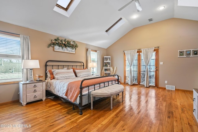 bedroom with multiple windows, light hardwood / wood-style floors, and vaulted ceiling with skylight