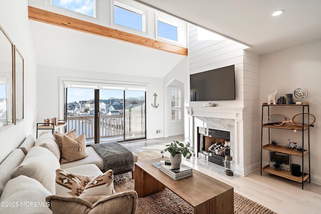 living room featuring a fireplace, high vaulted ceiling, beam ceiling, and light wood-type flooring