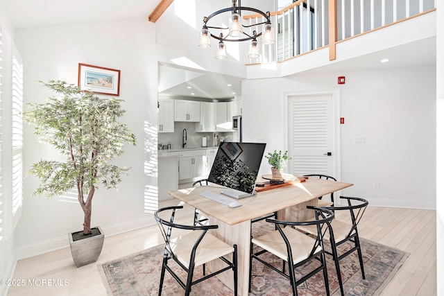 office with high vaulted ceiling, sink, a chandelier, beam ceiling, and light hardwood / wood-style flooring