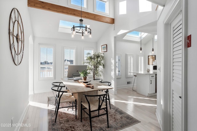 dining area with light hardwood / wood-style flooring, a towering ceiling, a skylight, beam ceiling, and a chandelier