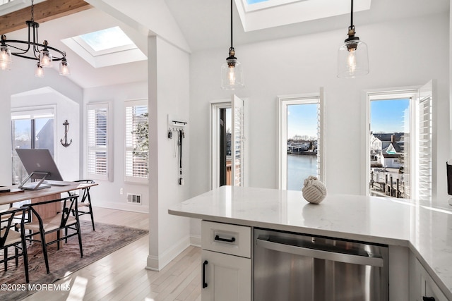 kitchen with decorative light fixtures, vaulted ceiling with skylight, dishwasher, and white cabinets